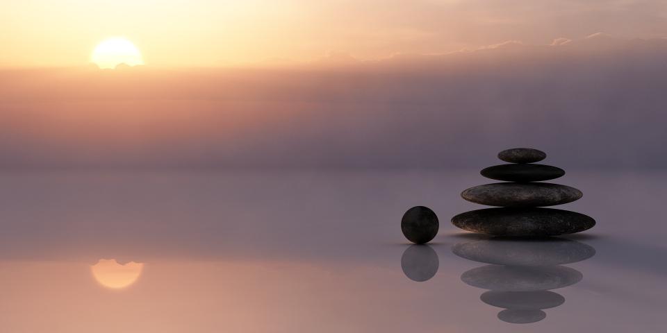 Photo d'un couché de soleil avec la vue sur la mer et des cailloux de méditation