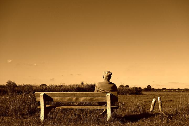 Photo d'un homme âgé assis sur un banc regardant l'horizon
